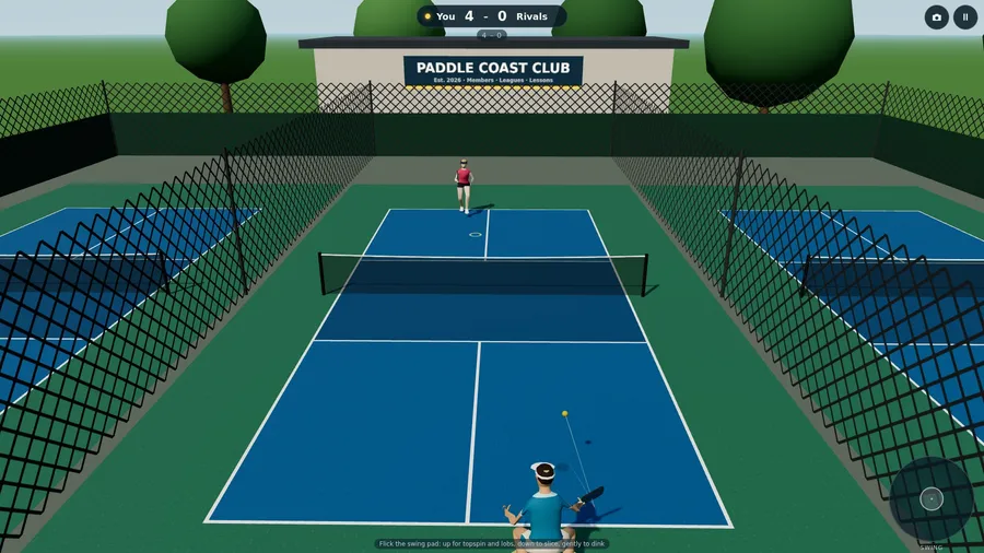The outdoor courts, with chain-link fences and trees, during a singles point.