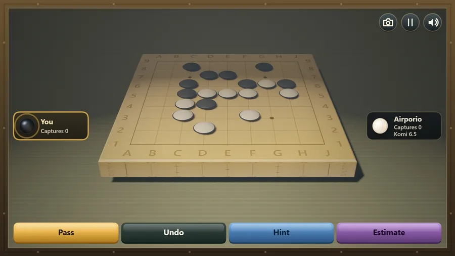 Seat camera low at your side of the 3D 9×9 goban mid-game, You against Airporio, with Pass, Undo, Hint and Estimate